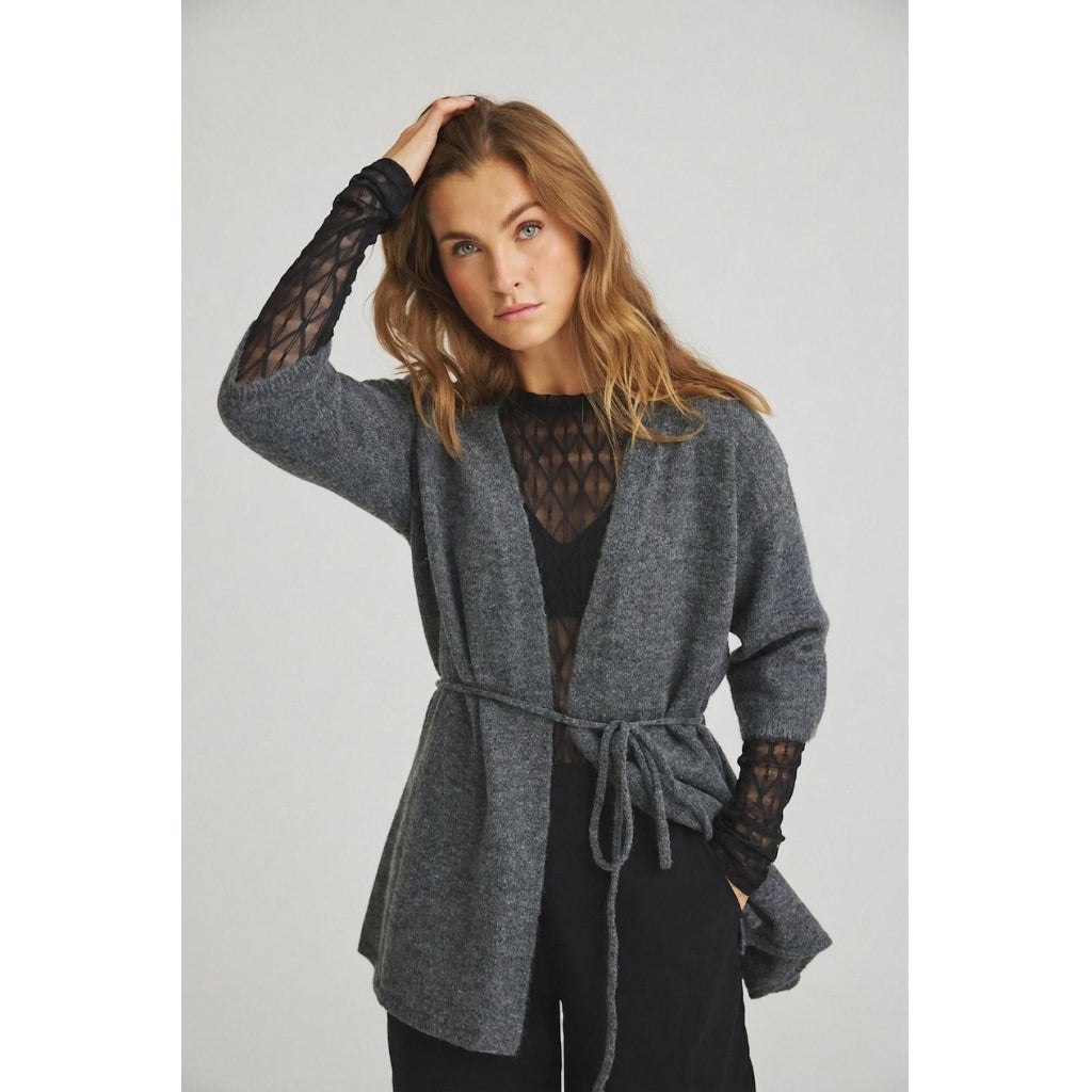 En person har en grå LUXZUZ 156420 – Segberg Sort cardigan med åben front på over en sort, feminin, gennemsigtig langærmet top.