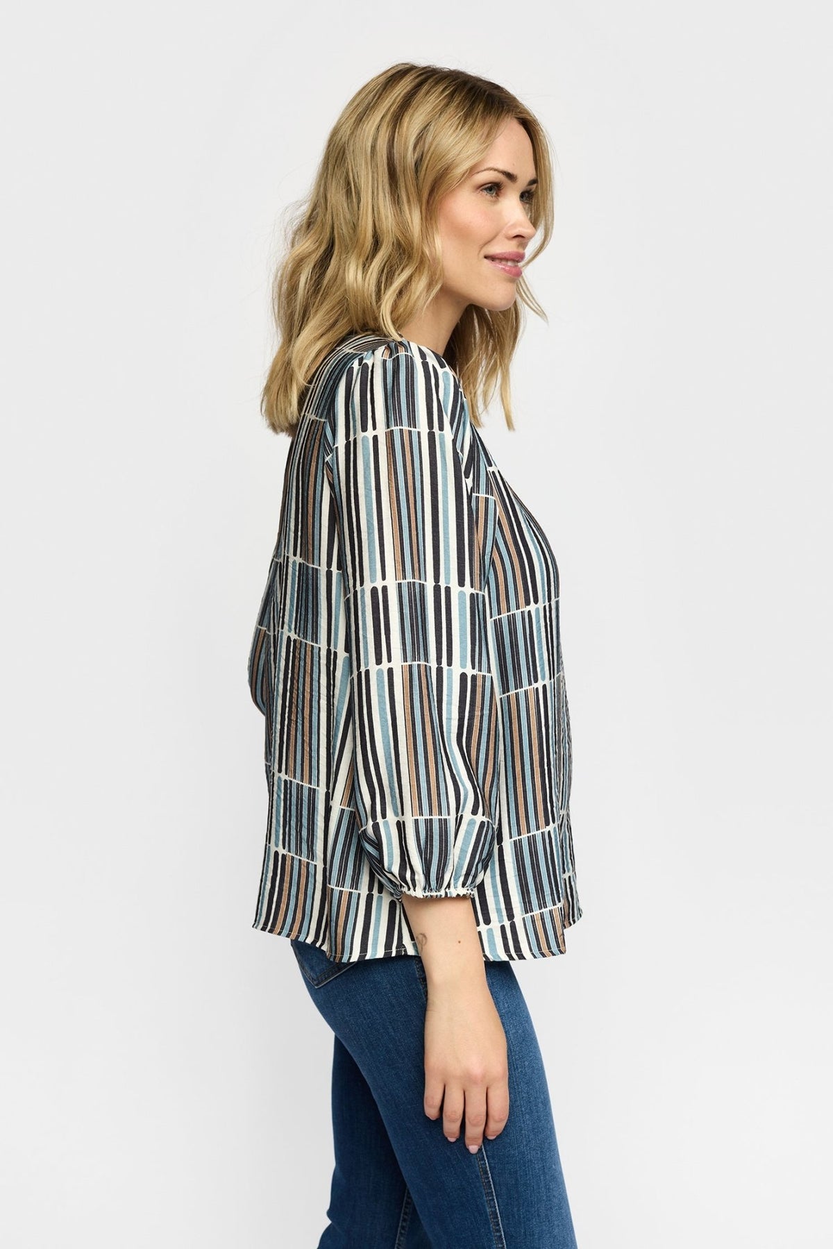 En kvinde iført en 2-Biz Esmara Blå-mønstret bluse og blå jeans, set i profil på en ensfarvet hvid baggrund.