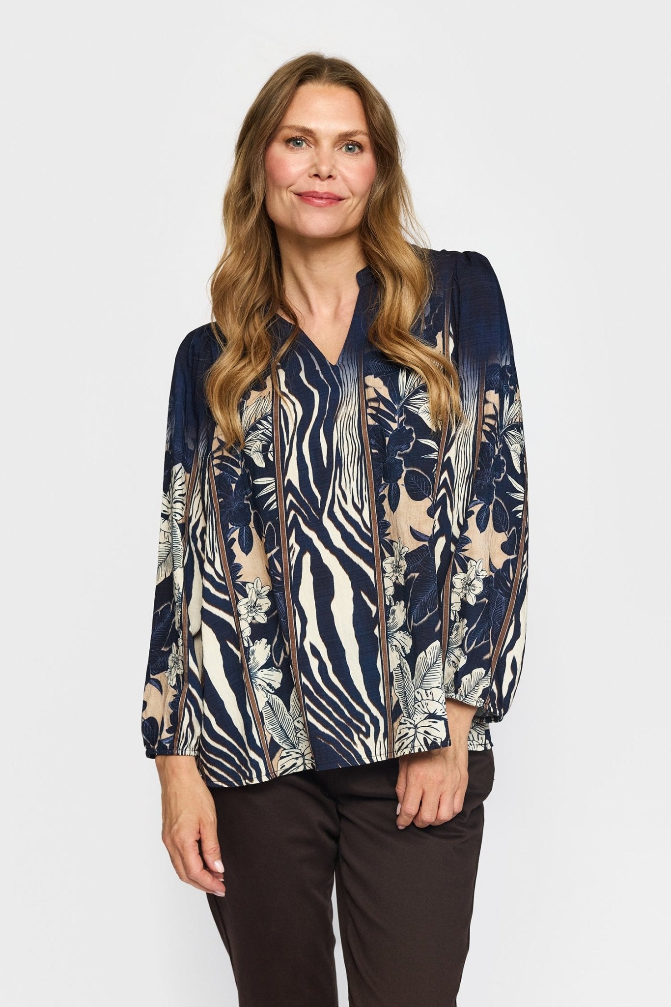 Kvinde i 2-Biz – Lise Mørkeblå, en marineblå bluse med blomster- og zebramønster, foran en ensfarvet hvid baggrund.