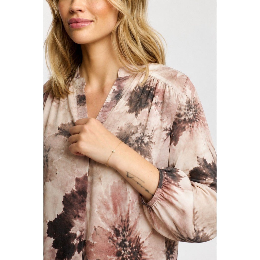 Kvinde i 2-Biz – Bluse med Eve Brun-mønster med abstrakt blomsterprint og en tatovering på hvid baggrund.