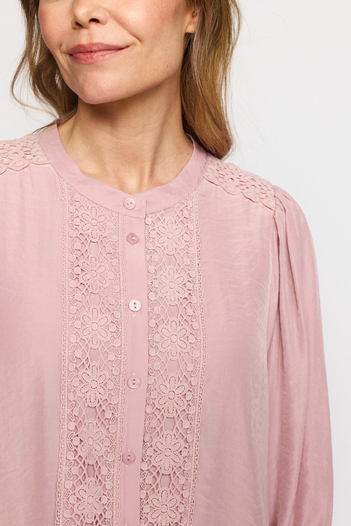 Kvinden har en 2-Biz Karoline Rosa på: en feminin bluse med blomsterblonder og knapper foran.
