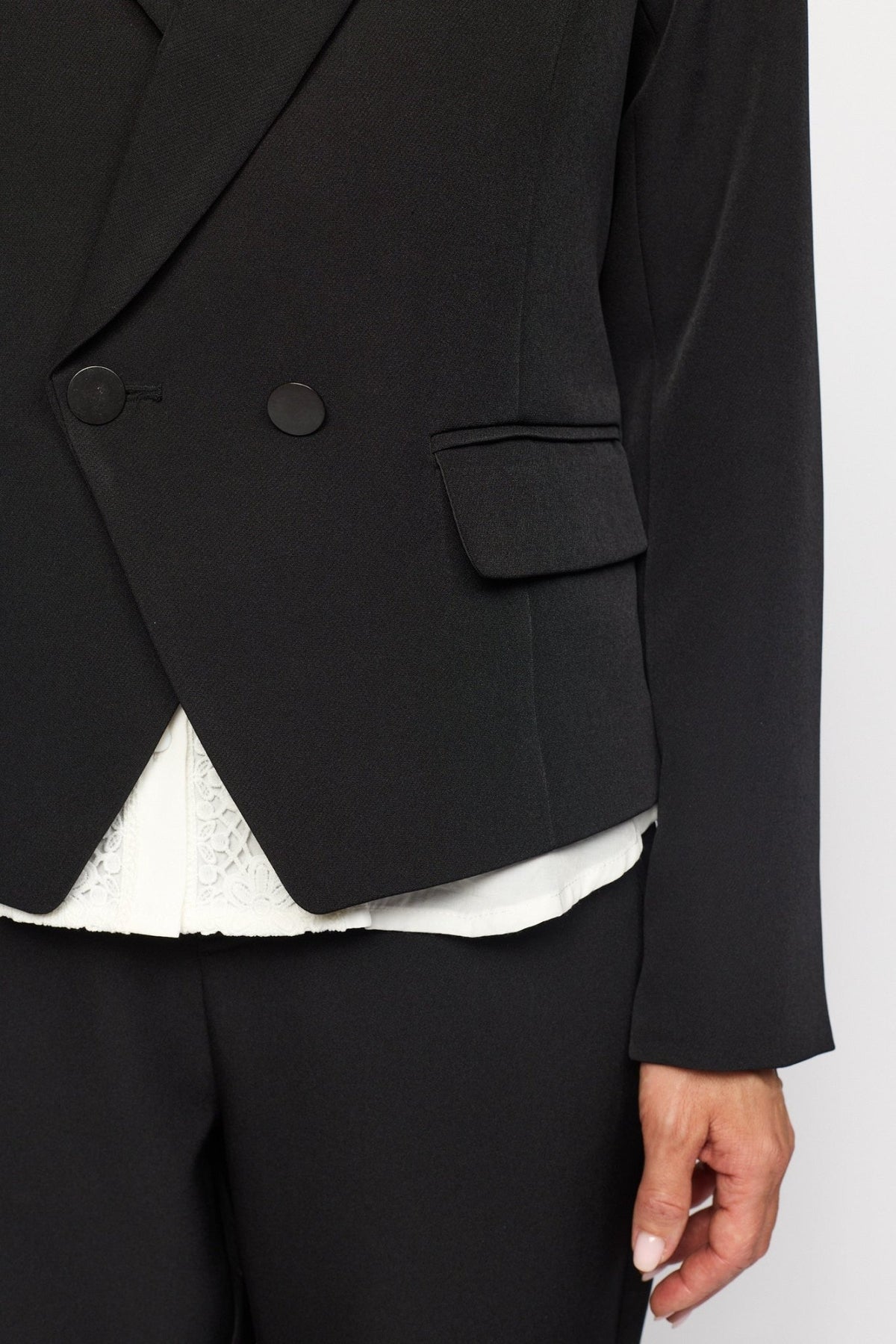 Sort 2-Biz Judith Sort dobbeltradet blazer, båret over en hvid top med blonder.