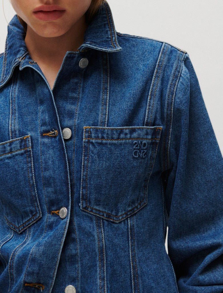En person har 2NDDAY Billa Denim-truckerjakken på med sølvknapper og teksten »2ND GVS« på lommen.