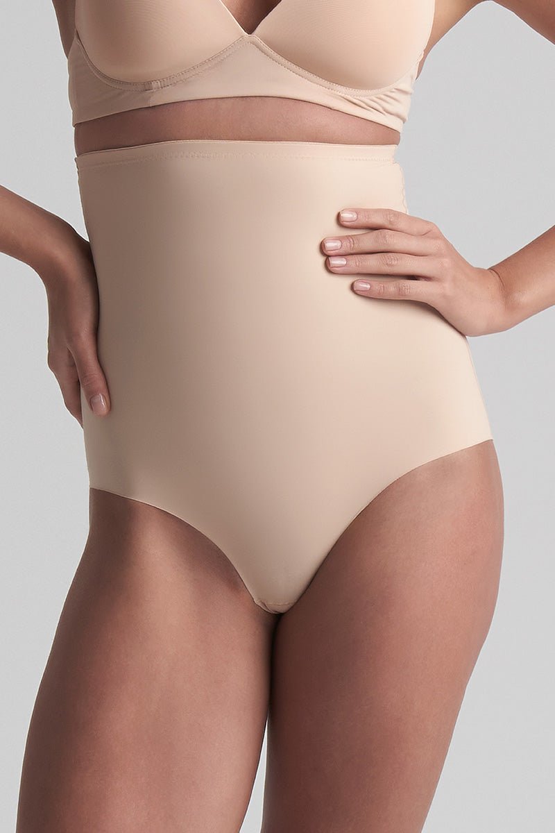 Model iført BYE BRA 151135 trusser med høj talje i farven Pudder og matchende bh, der poserer foran en ensfarvet baggrund.