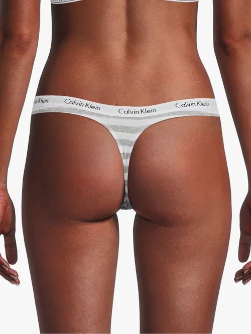 Model i grå og hvid Calvin Klein 143085 g-streng med ikonisk logo i linningen, en del af 3 FOR 399,- Stribet-tilbuddet.