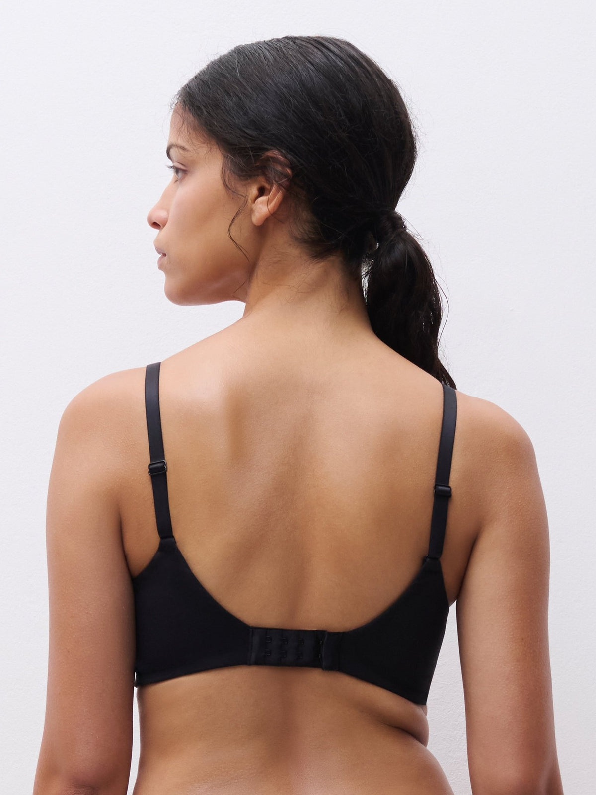En kvinde med mørk hestehale bærer en Chantelle EasyFeel – Easy Bliss Black Sort-bh, set bagfra.