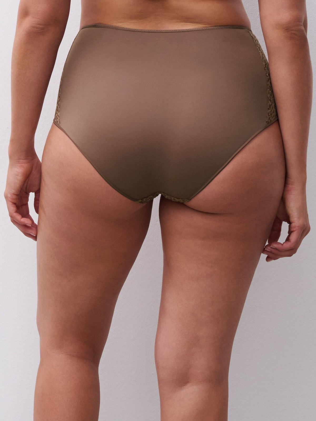 Modellen bærer Chantelle EasyFeel 153676 Norah Wild Brown maxi-trusse med blonder i siderne, vist bagfra på en ensfarvet baggrund.