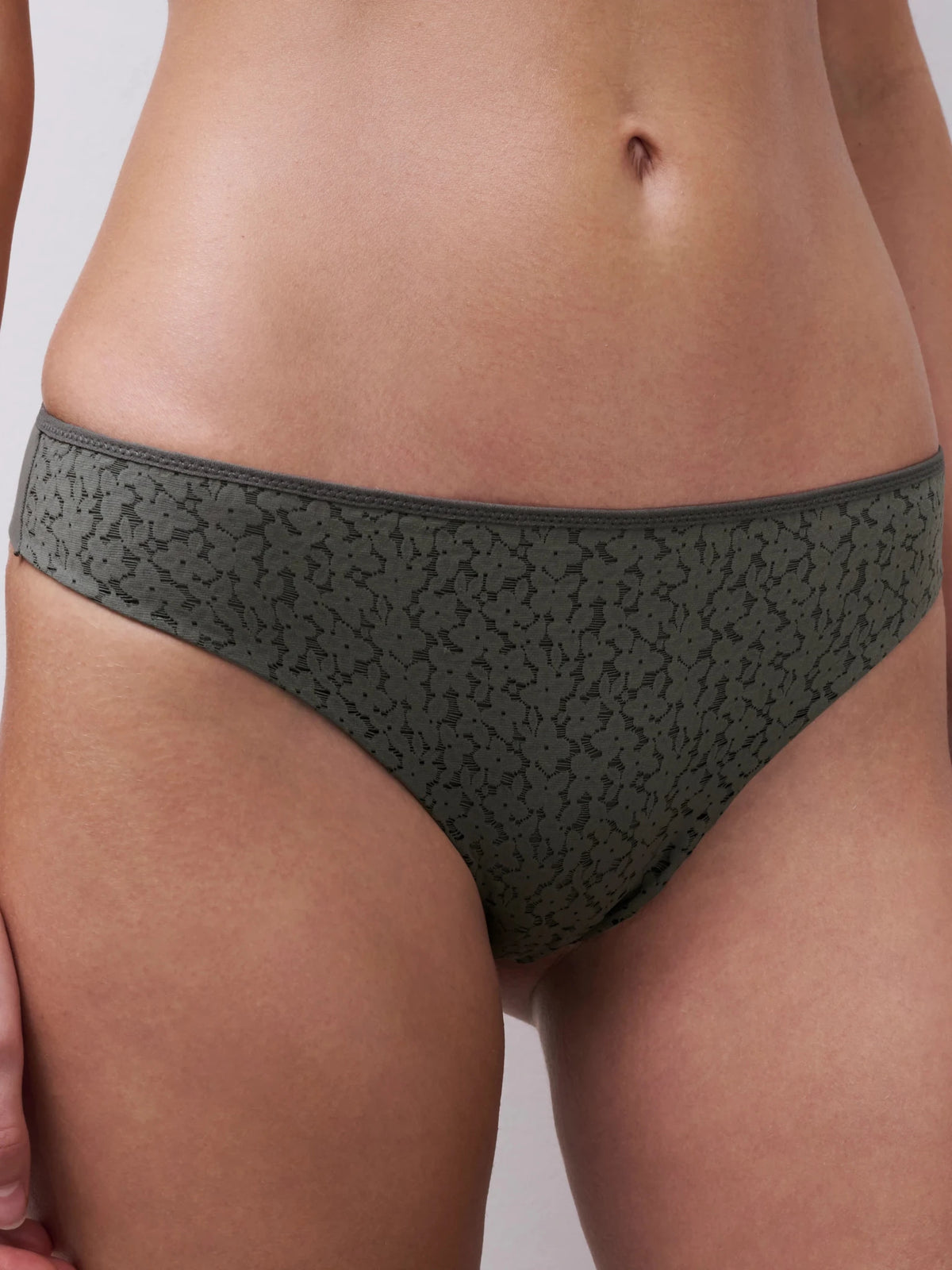 Nærbillede af en person, der bærer Chantelle EasyFeel Norah Vert Argile Grå undertøj i bikini-stil foran en ensfarvet baggrund.