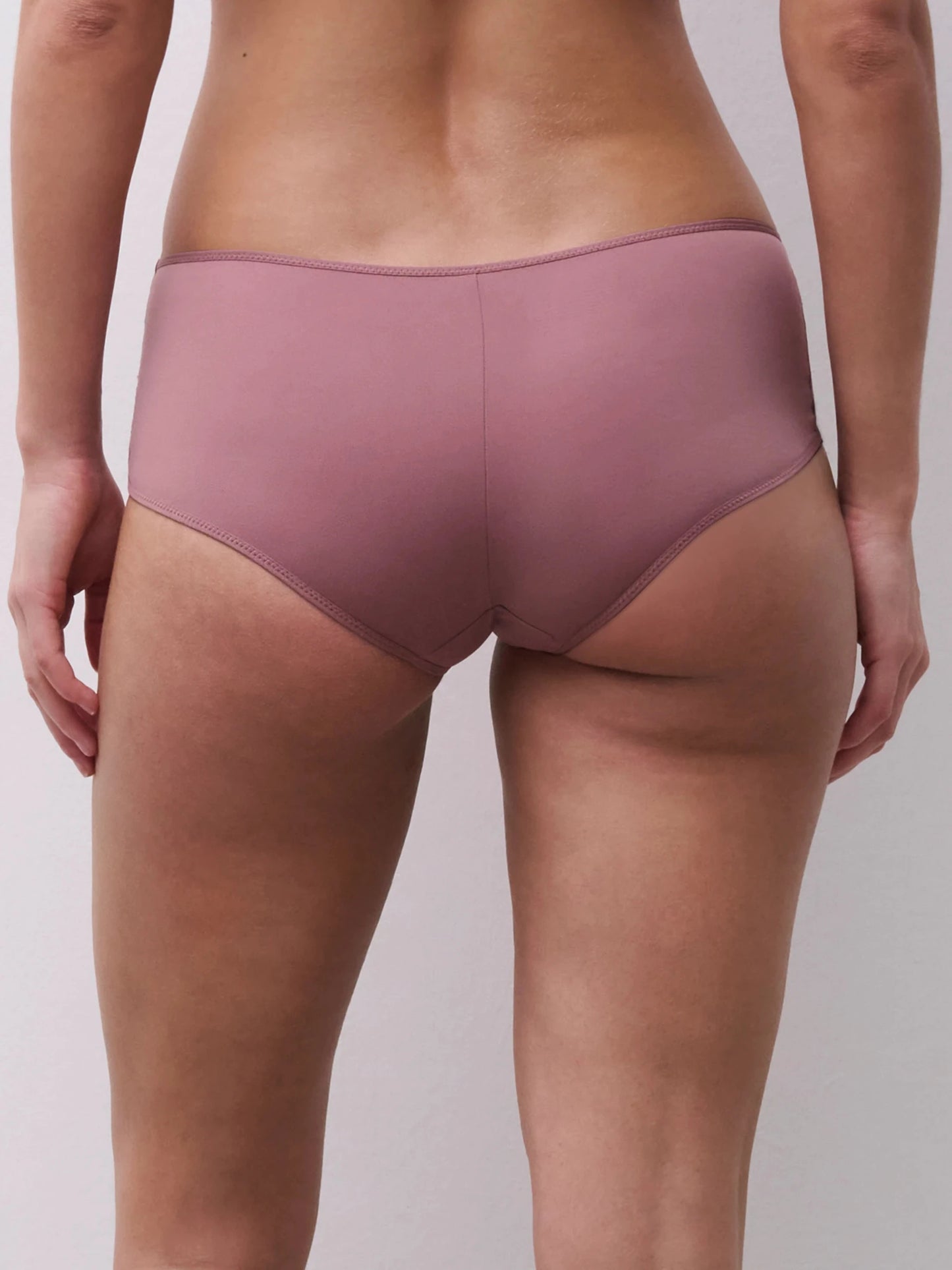 Model iført Chantelle EasyFeel – Floral Touch Rose Des Bois hipster, set bagfra, på lys ensfarvet baggrund.