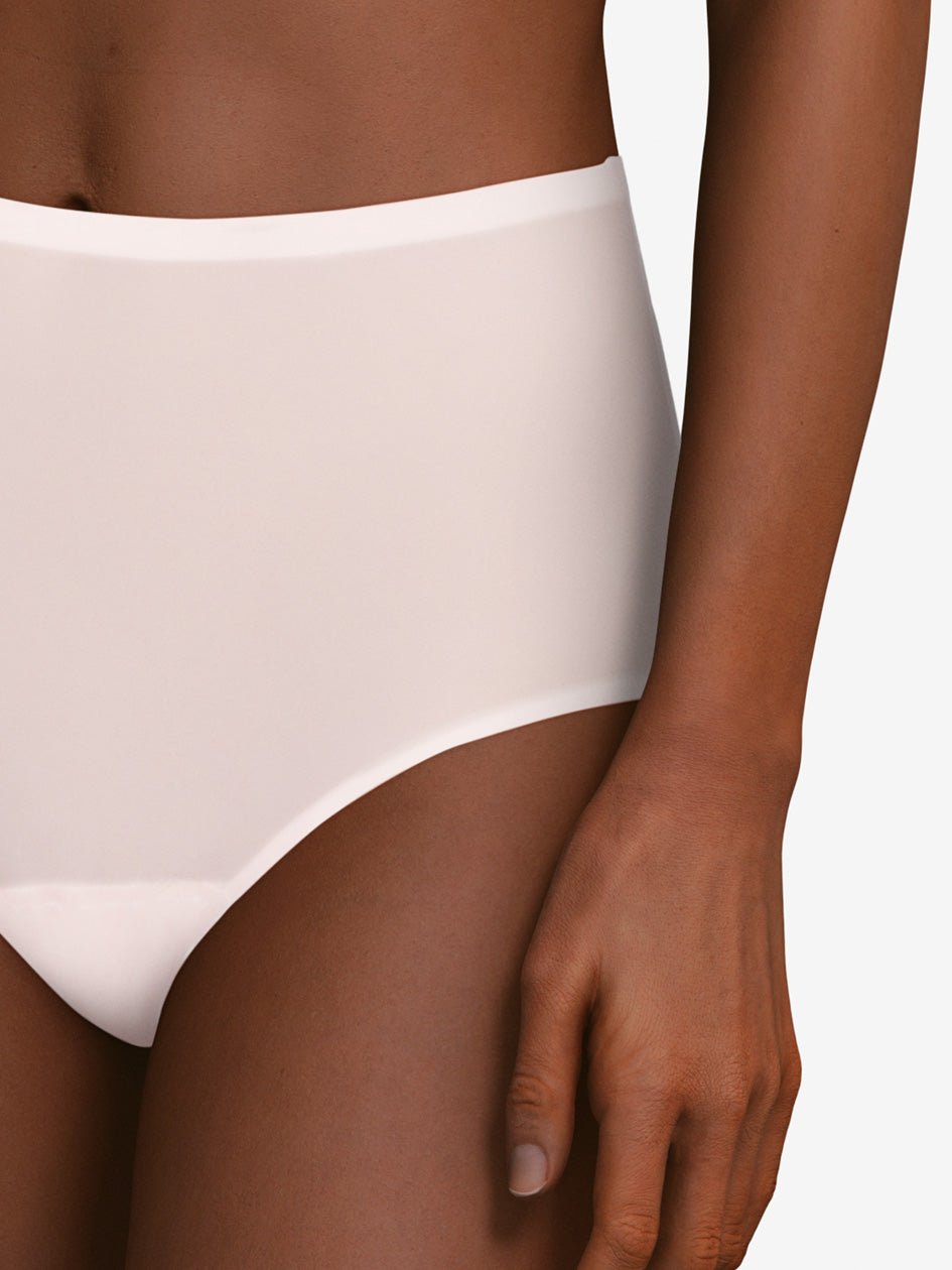 Modellen bærer en Chantelle Seamless Soft Stretch Maxi LYSERØD trusse, med den ene arm ned langs siden, på en ensfarvet baggrund.