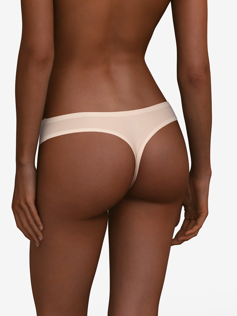En person viser Chantelle Seamless - Soft Stretch String Sand 130753 set bagfra på en ensfarvet hvid baggrund.