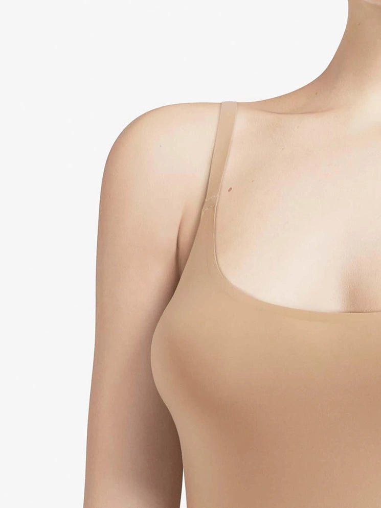 Modellen bærer en Chantelle Seamless Soft Stretch-camisole i farven Sand med tynde stropper, vist fra skulderen til den nedre del af brystet.
