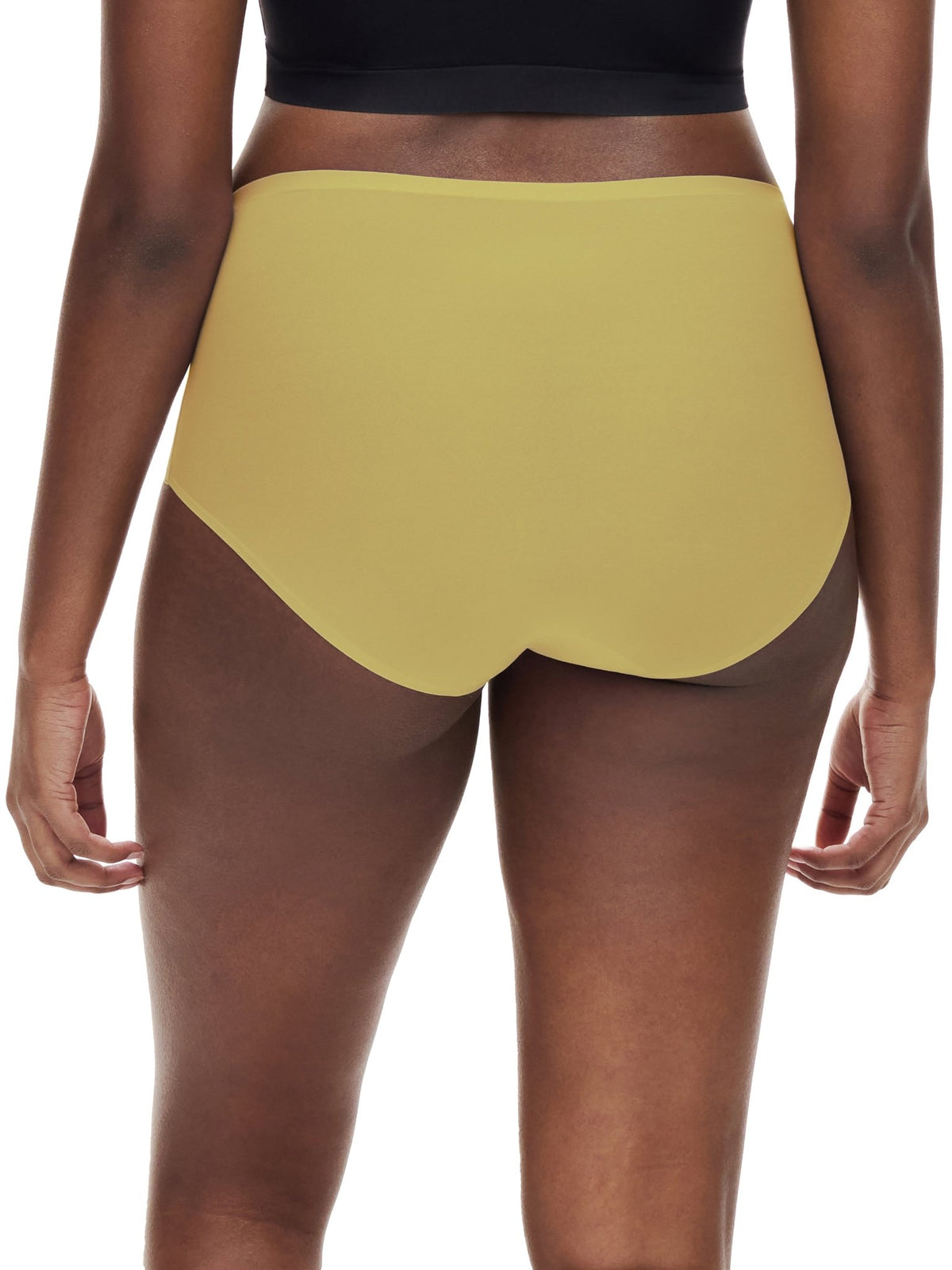 En person iført en gul Chantelle Seamless Soft Stretch Maxi Gul-trusse og en sort top, set bagfra på hvid baggrund.