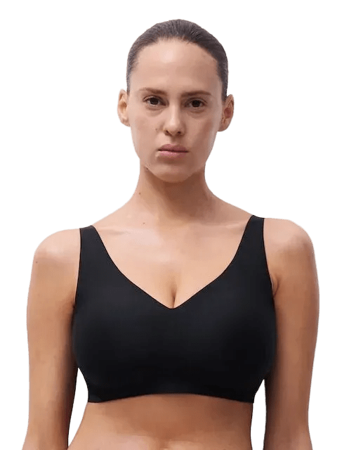 En kvinde iført en Chantelle Seamless 152392 Soft Stretch Power Sort bh uden bøjle, der står foran en hvid baggrund.
