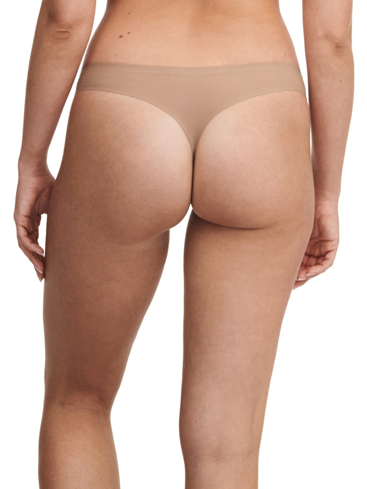 Modellen bærer Chantelle Seamless 153058-string i farven Latté, set bagfra, fremstillet af blødt, elastisk materiale.