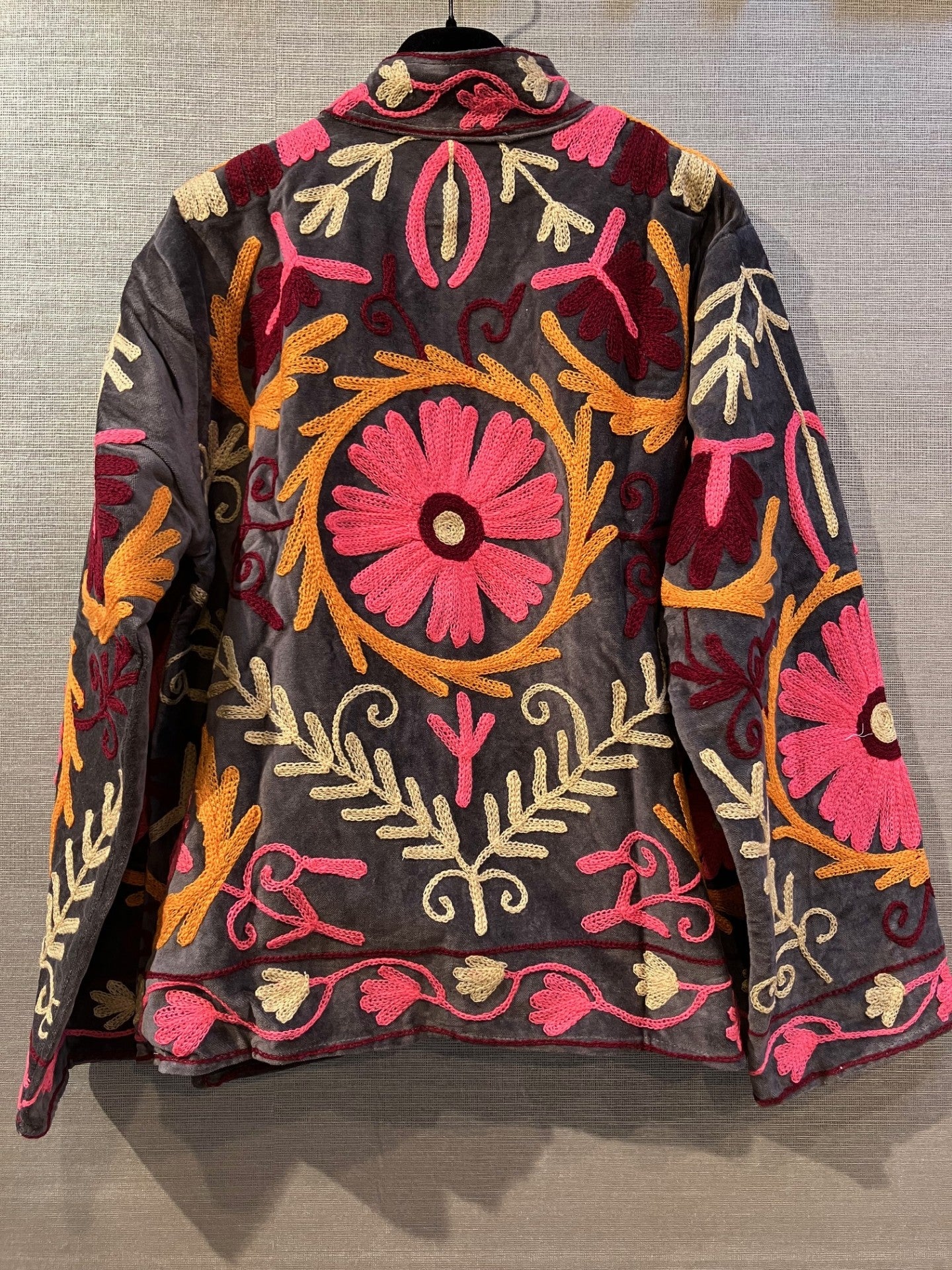 Cabana Living 155955 Rif Grå: Sort jakke med markante blomstermønstre i pink, gul og orange på ryggen, ærmerne og nederkanten.