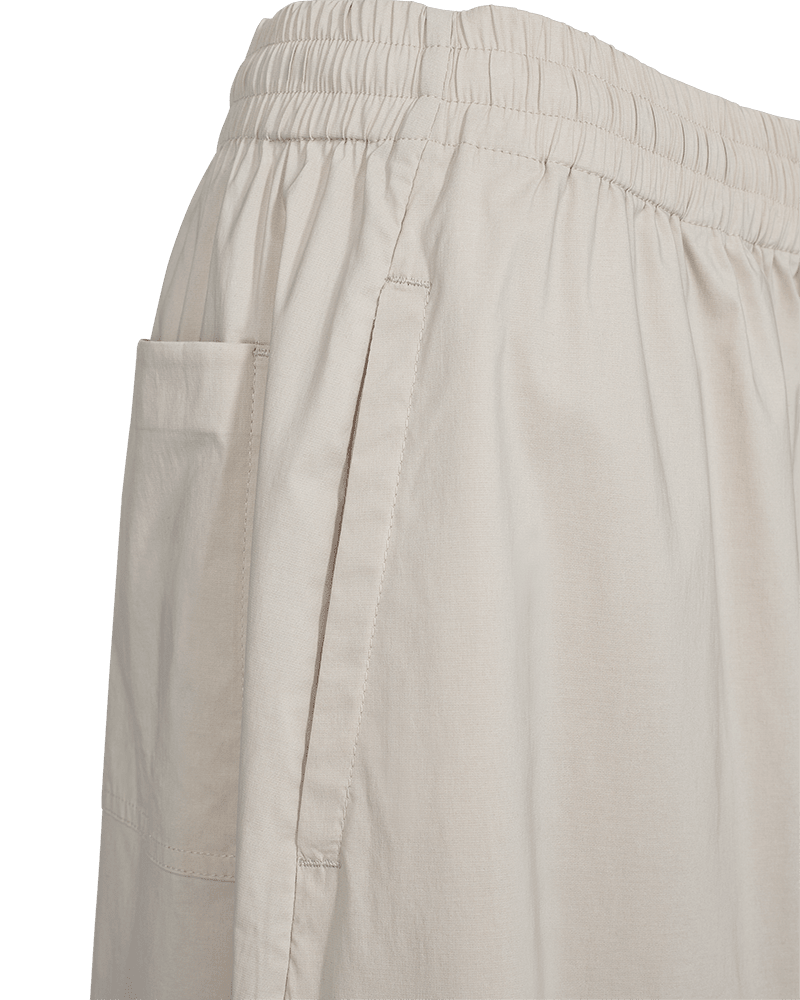 Nærbillede af Freequent Jules-bukser i beige med elastisk linning, brede ben, lomme i sidesømmen og påsyet lomme bagpå.