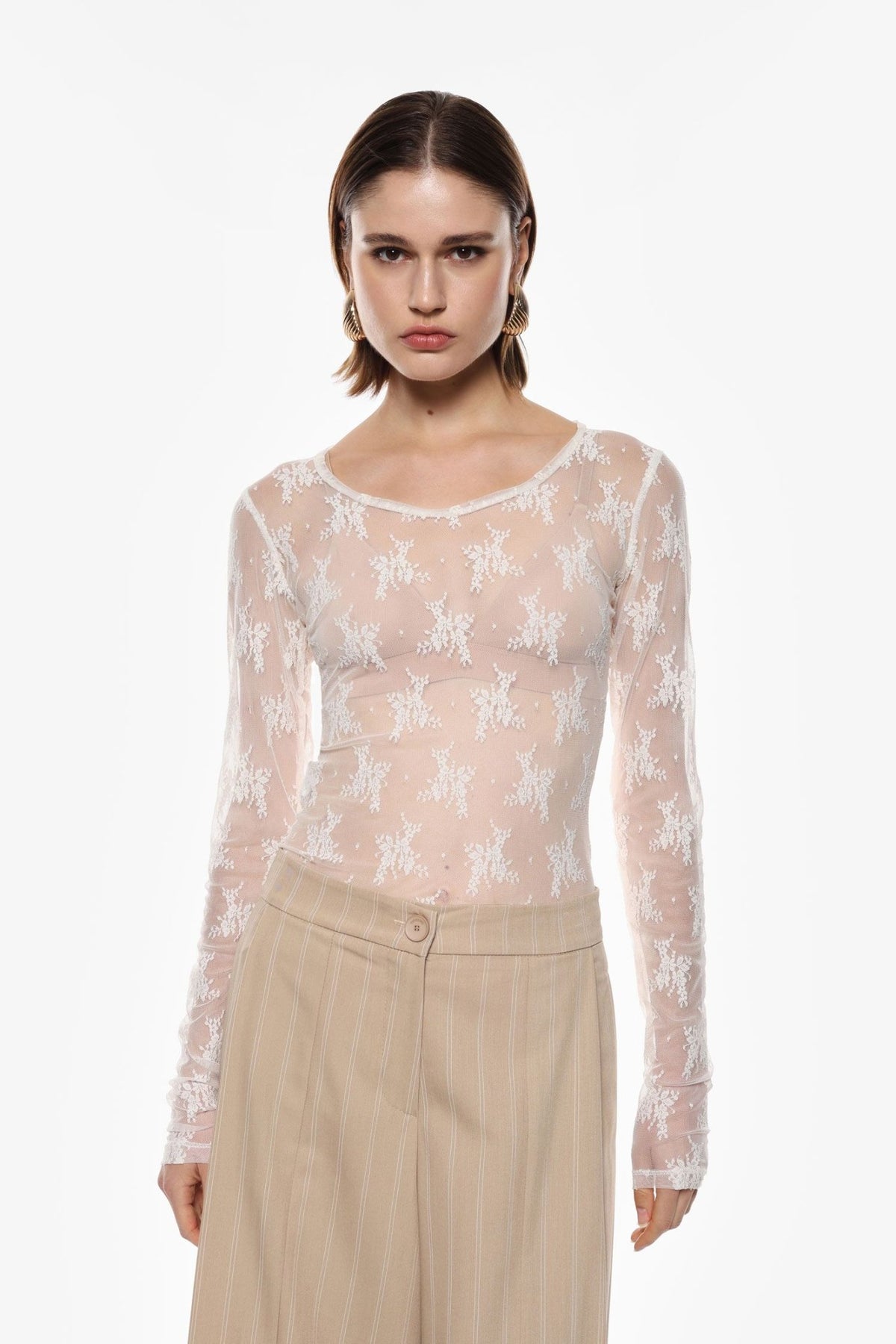En kvinde iført en offwhite bluse fra Imperial 152581 TW91, der står foran en klar hvid baggrund.