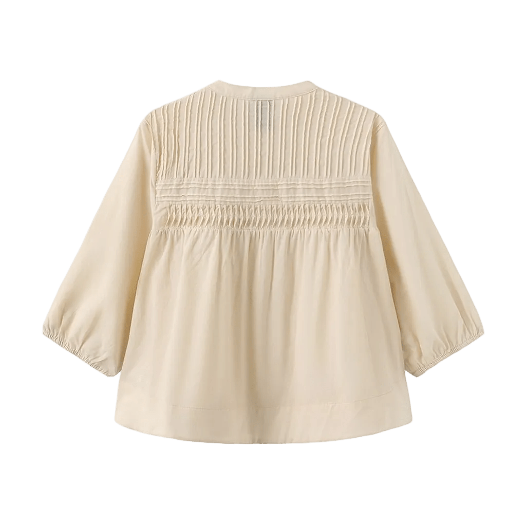 Luxzuz Percha Beige: Cremefarvet langærmet bluse med plisseret og smocket overdel på ryggen, vist på ensfarvet baggrund.