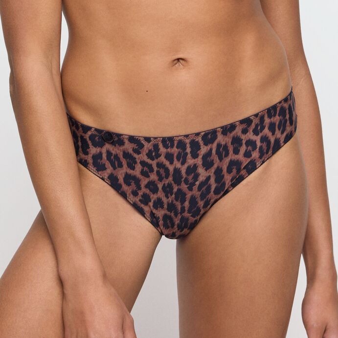 Model iført Marie Jo Tom Fauve Leopard-bikinibukser, med den ene hånd på låret, der poserer foran en ensfarvet lysegrå baggrund.