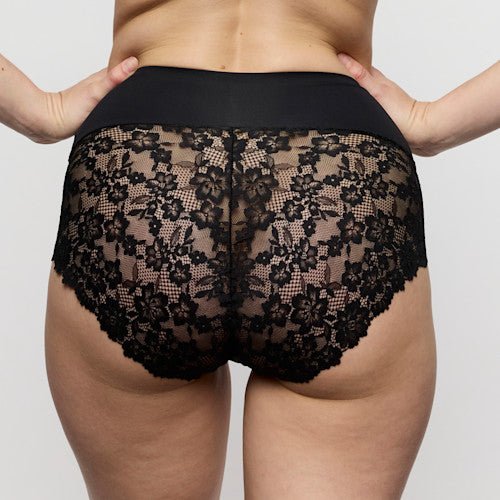 Model iført Marie Jo – Soft Studio Black Sort maxi-trusser med høj talje, set bagfra, ensfarvet baggrund.