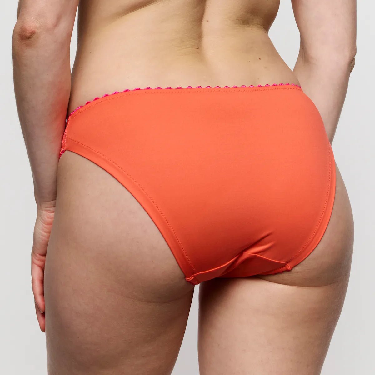 Modellen viser Marie Jo - Solene Orange 154358 trusser set bagfra, hvilket fremhæver pasformen og broderidetaljerne på lys hud.