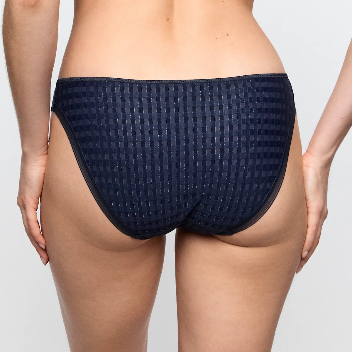 Model iført Marie Jo Avero Velvet Blue Mørkeblå undertøj, set bagfra, foran en ensfarvet lys baggrund.