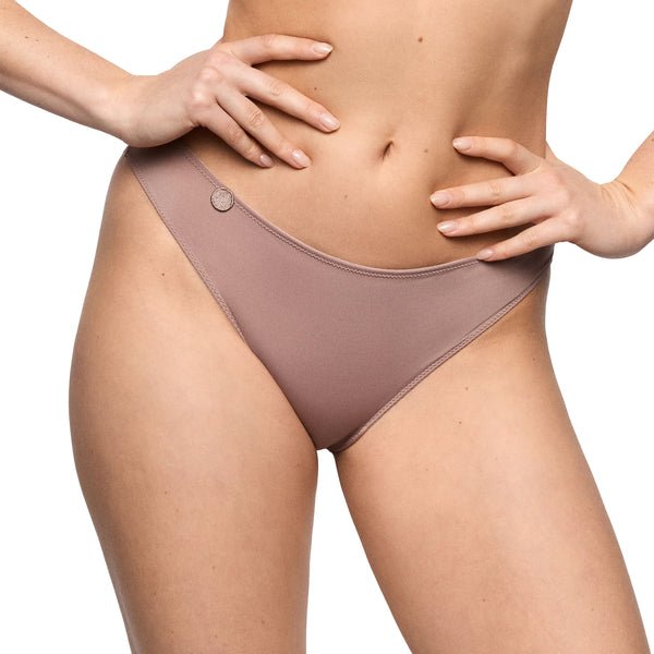 Model iført Marie Jo Tom Cosmetic Lysebrun 155297, med hænderne på hofterne, fotograferet foran en neutral baggrund.