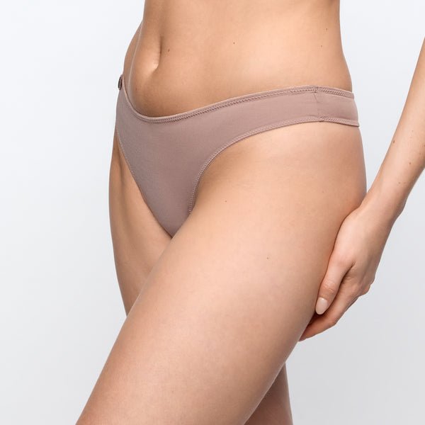 Model iført Marie Jo Tom Cosmetic Lysebrun bikiniunderdel med høj talje, der går fra taljen til midt på låret, foran en ensfarvet baggrund.
