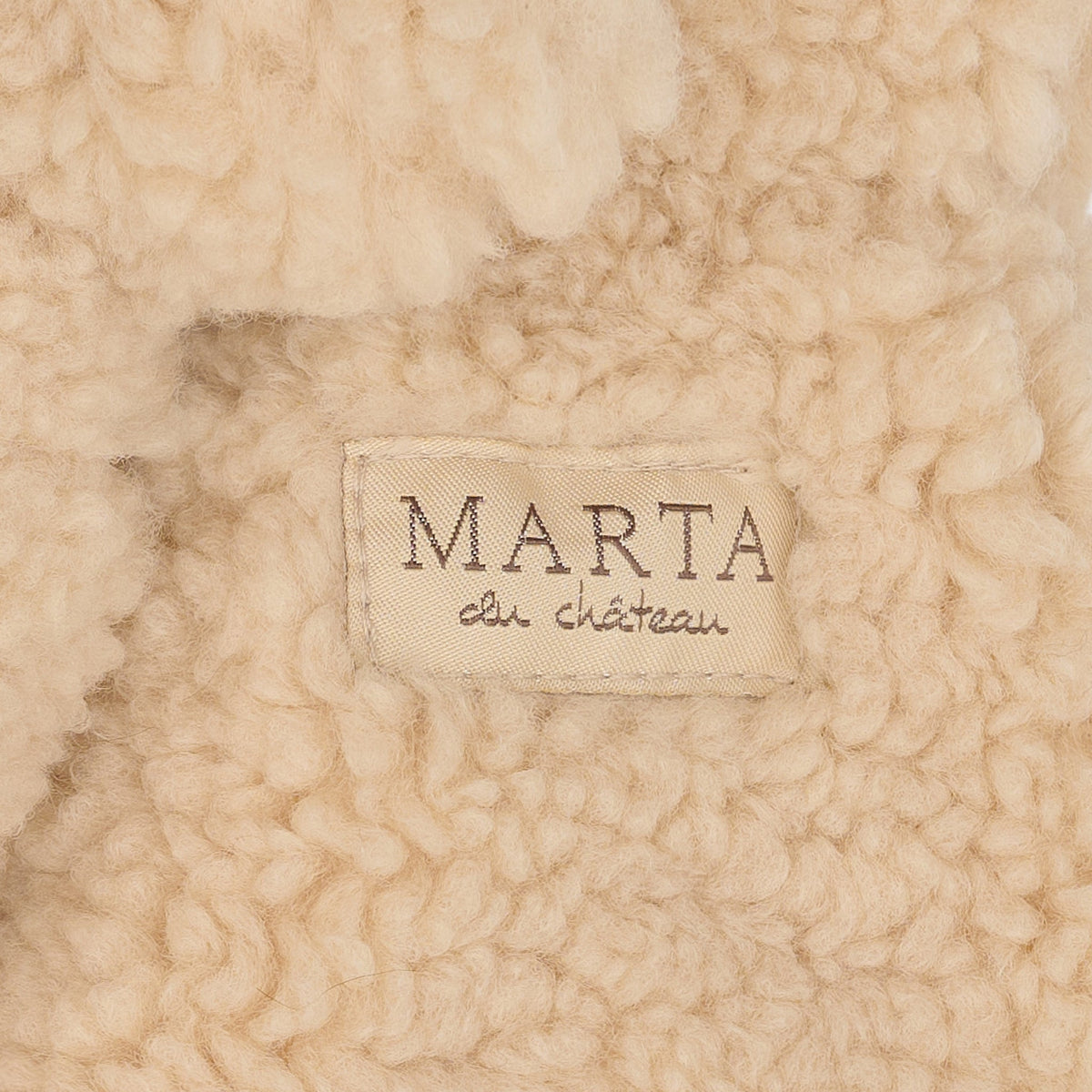 Nærbillede af Teddy Mitten Sand-uld med Marta du Château-mærket syet på.