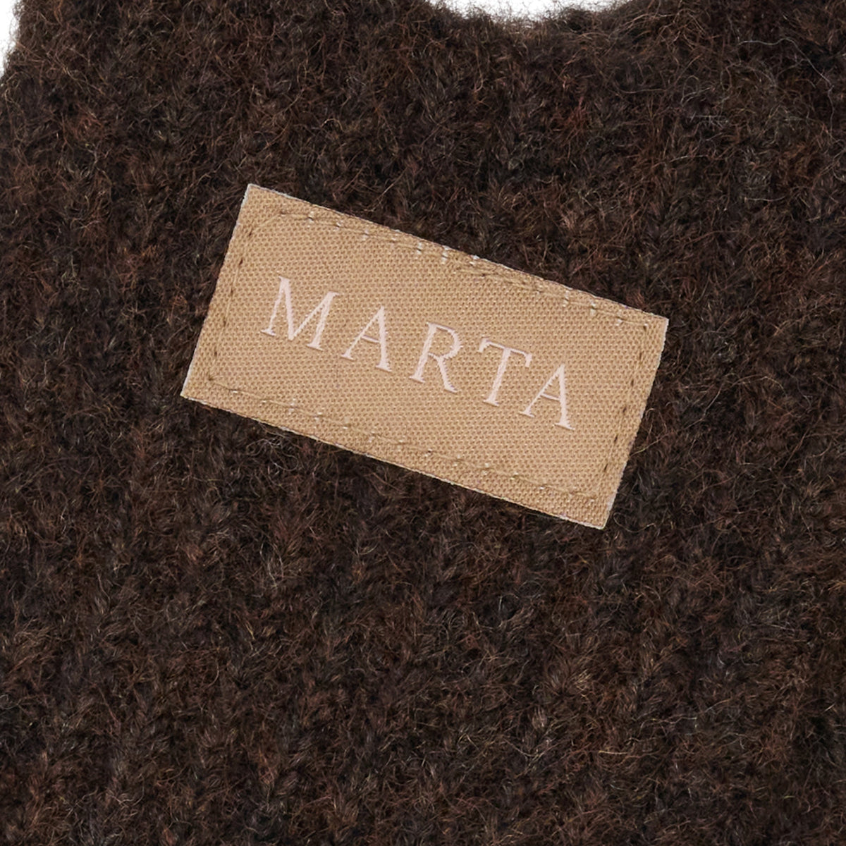 Mørkebrunt, struktureret stof med en beige etiket med påskriften »MARTA«, der er perfekt til Marta du Château Vanessa-strikkede handsker.