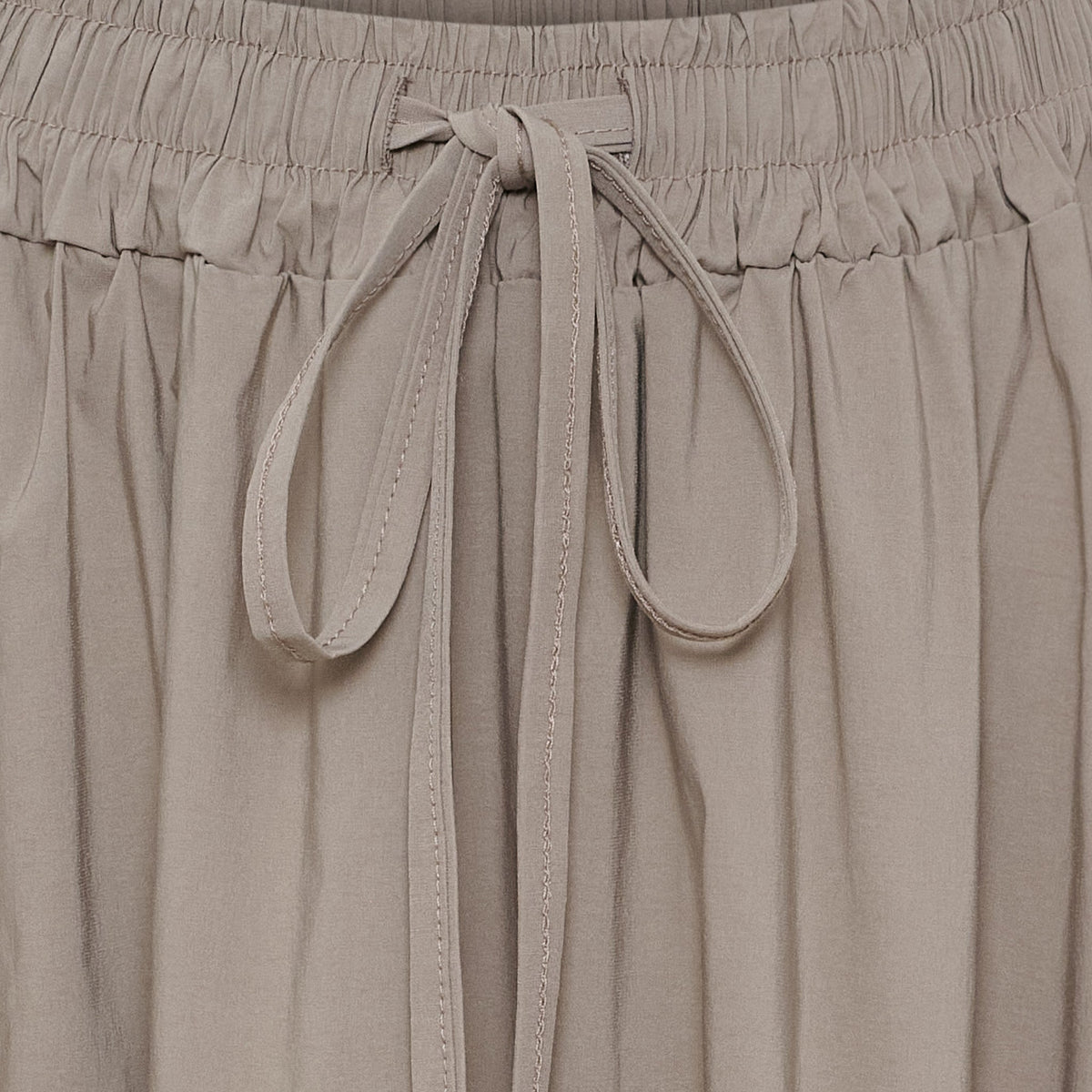 Nærbillede af Marta du Château Pomeline Sand-bukser med beige elastisk linning og sløjfe af stof i linningen.