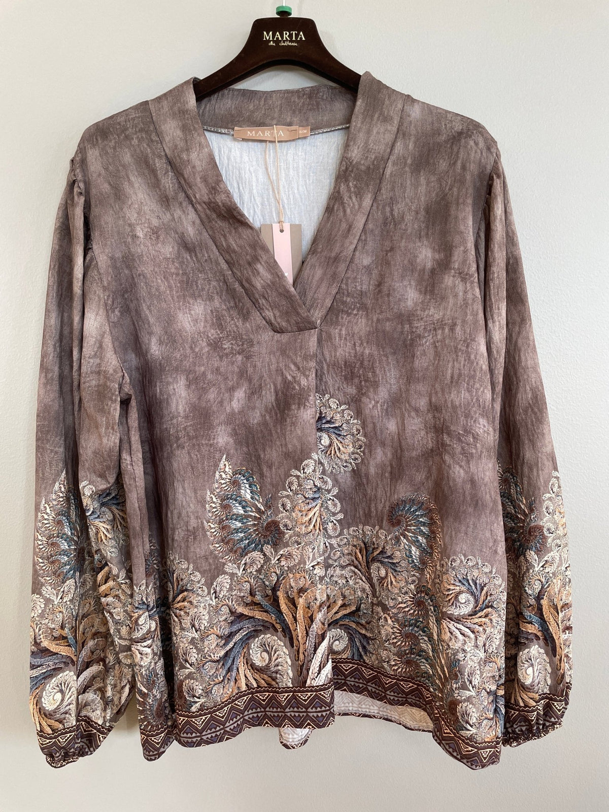 Marta du Château 156091 MDC: En smuk, brun mønstret bluse, der hænger elegant op ad en neutral væg.