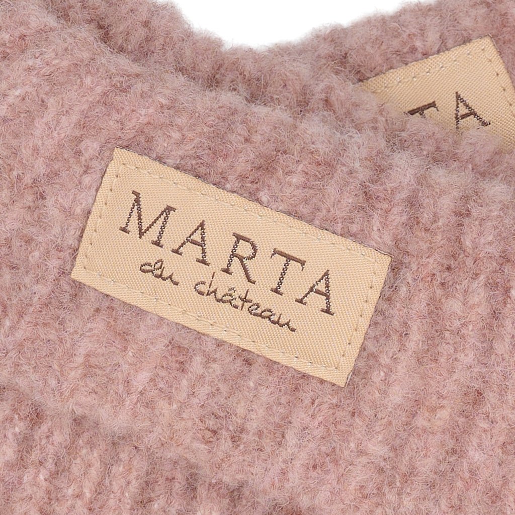 Nærbillede af et beige Marta du Château-mærke på blødt lyserødt ribstrikket stof, MDCLindsey Rosa 156247.