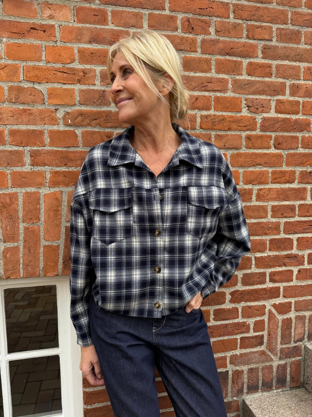 Kvinde iført en mørkeblå ternet 156371 | Marta du Château - MDCMarbella-skjorte og mørke denimjeans.