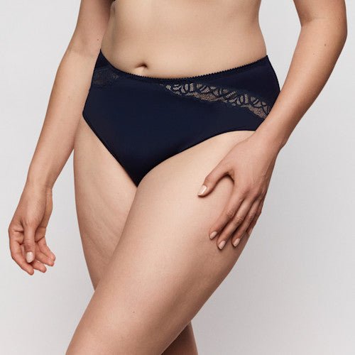 En kvinde iført et PrimaDonna Salerno Midnight Blue maxi-trusse med blonder, der står foran en ensfarvet baggrund.