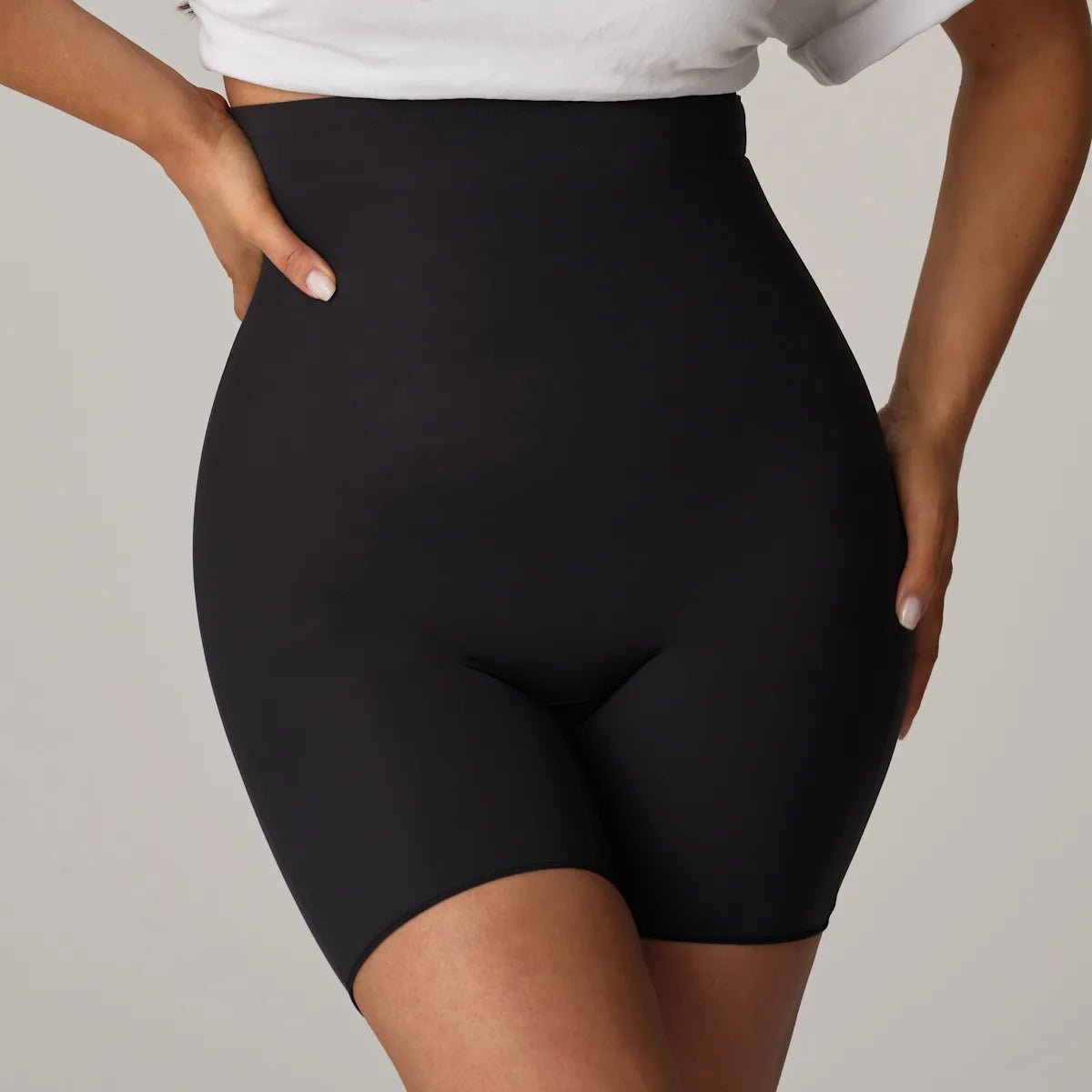 Kvinde iført PrimaDonna Perle Charcoal Mørkegrå formende shorts og en hvid crop top, der skaber en glat silhuet.