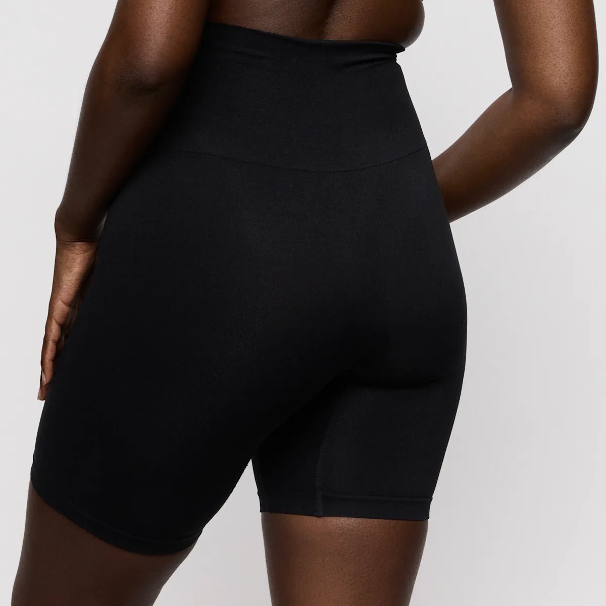 Model iført PrimaDonna – Nudda Black Sort shorts med høj talje, vist bagfra med hånden på hoften for at fremhæve den slanke silhuet.