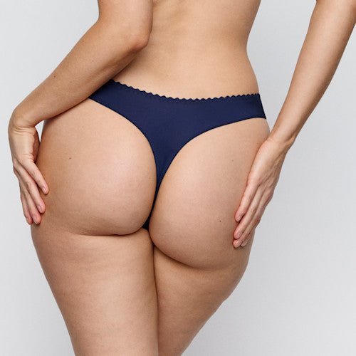 Model iført PrimaDonna San Angel Water Blue G-streng, set bagfra, med hænderne på hofterne, foran en ensfarvet baggrund.