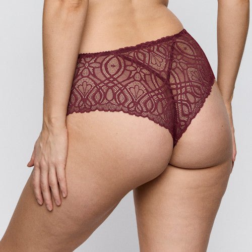 Model iført PrimaDonna 155417 G-streng i farven »Evening Red Bordeaux« med blonder, set bagfra mod en lys baggrund.
