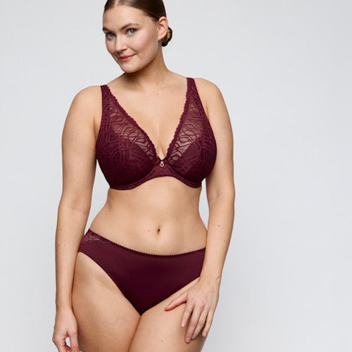 Model iført PrimaDonna 155421-sæt i burgunderfarvet blonder, fremstillet af genanvendte materialer, fotograferet foran en lys baggrund.