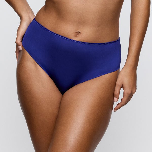 Modellen har PrimaDonna Shimla Crazy Blue Blå-trusser med høj talje på og står foran en ensfarvet lysegrå baggrund.