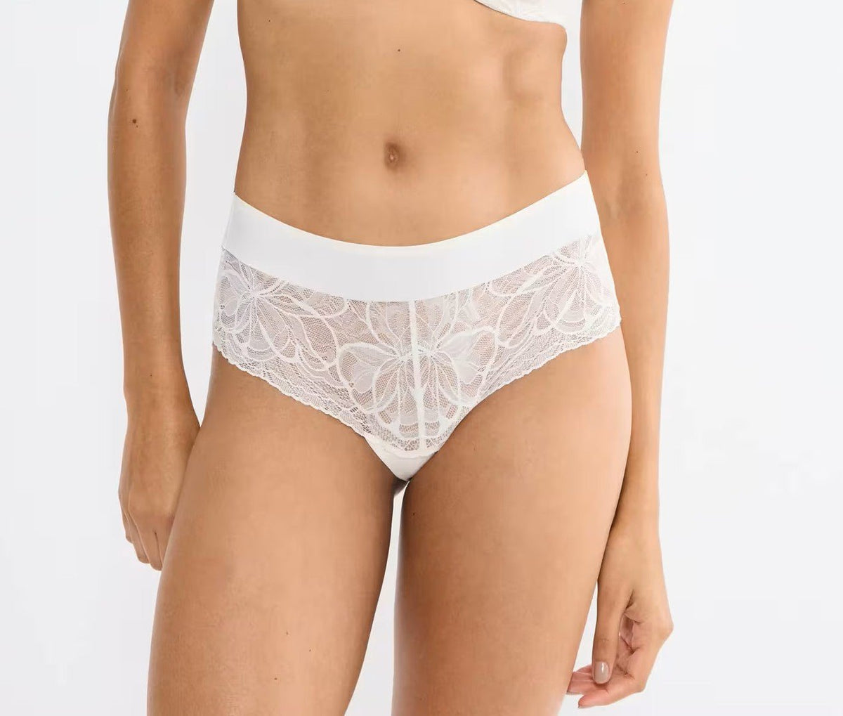Triumph Body Make-Up Illusion Lace 159 off-white trusser med blondemønster og bred linning, vist på en model.