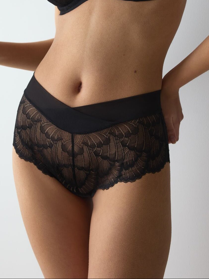 En kvinde iført Triumph Love In Lace 155876 0004 Sort undertøj står foran en ensfarvet hvid baggrund.