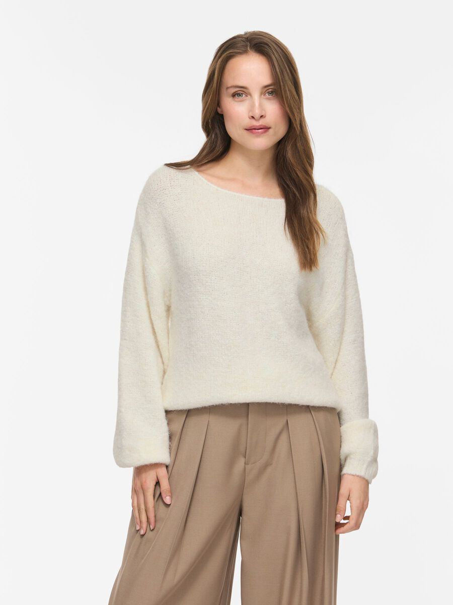 En kvinde iført en Vimarley Off White-top fra VILA, der står foran en ensfarvet hvid baggrund.