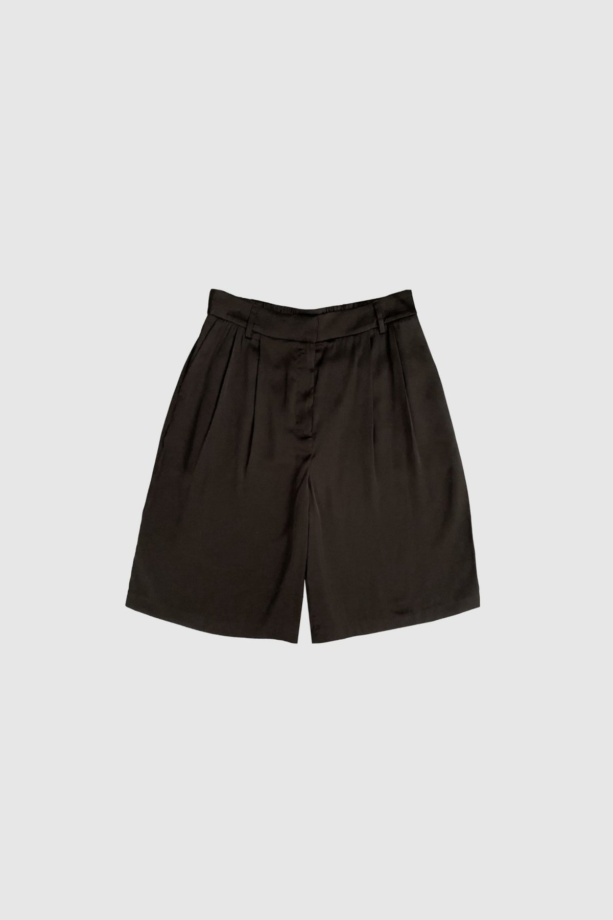 WithBlack – Paddie Mørkebrun: Shorts med høj talje, løs pasform og brede ben samt læg på en ensfarvet lysegrå baggrund.