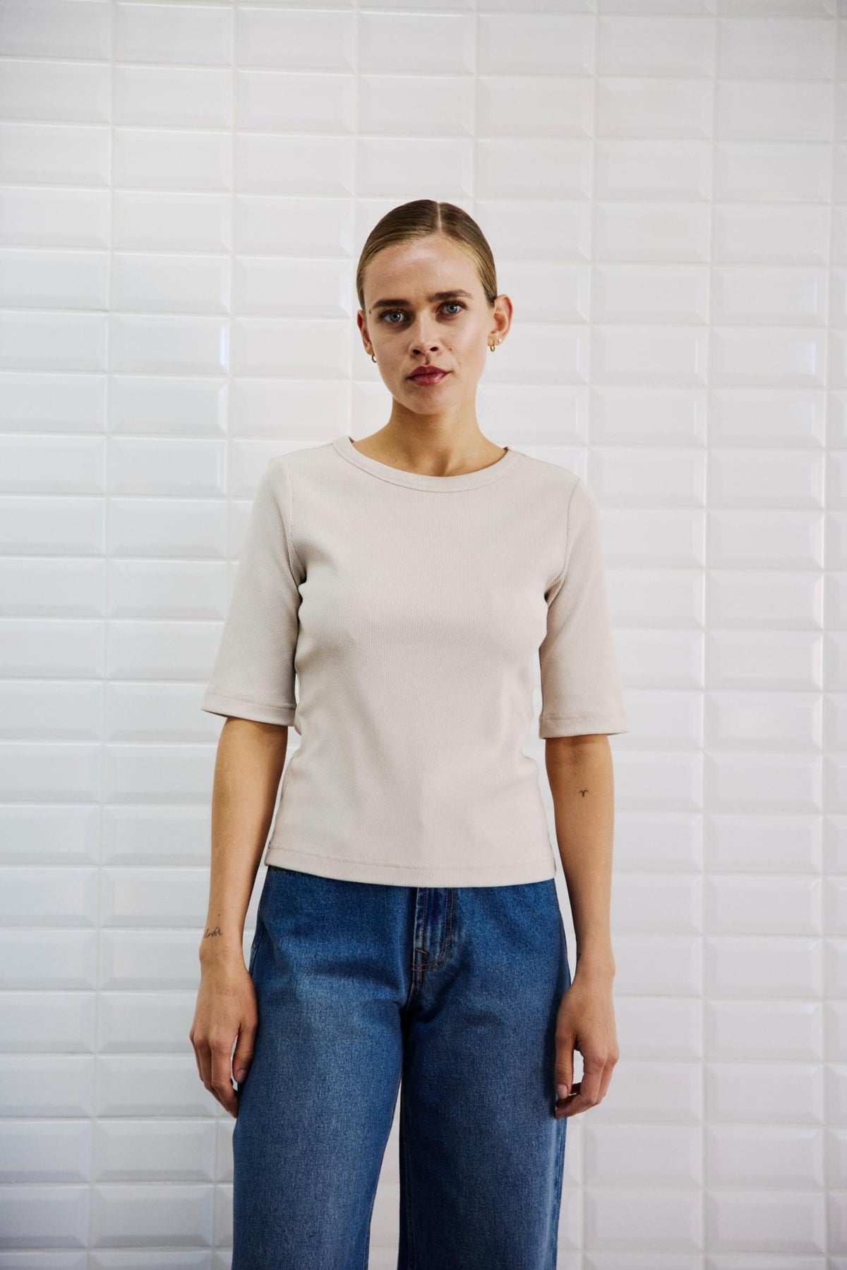 En kvinde iført en WithBlack WBLLullu beige T-shirt med ærmer, der går til albuen, og blå jeans.