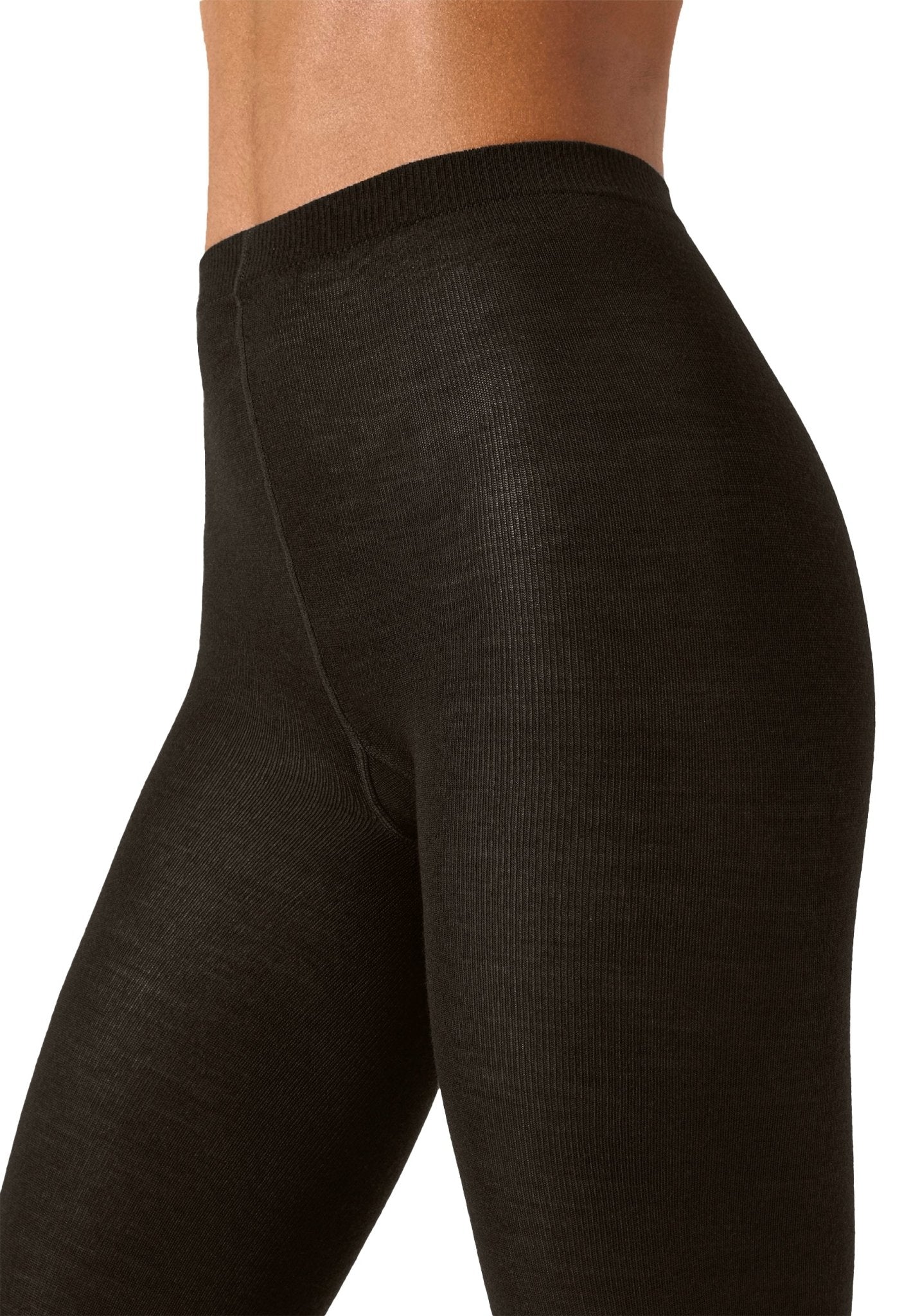 Modellen bærer Wolford Merino Mørkebrun-leggings; nærbillede af hofte og øvre lår, der fremhæver den ribbede struktur.