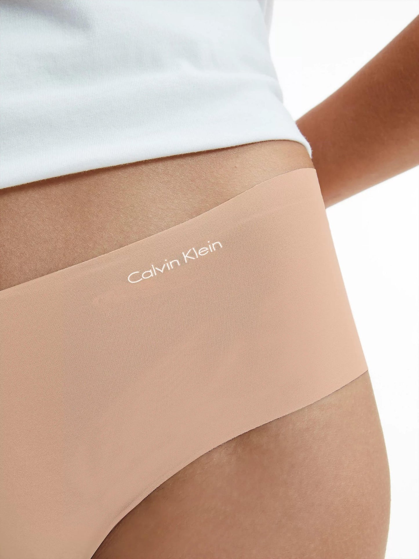 Her ses en nudefarvet G-streng fra Calvin Klein 146901 fra tilbuddet »3 for 399« stylet med en hvid skjorte, set fra siden ved hoften.