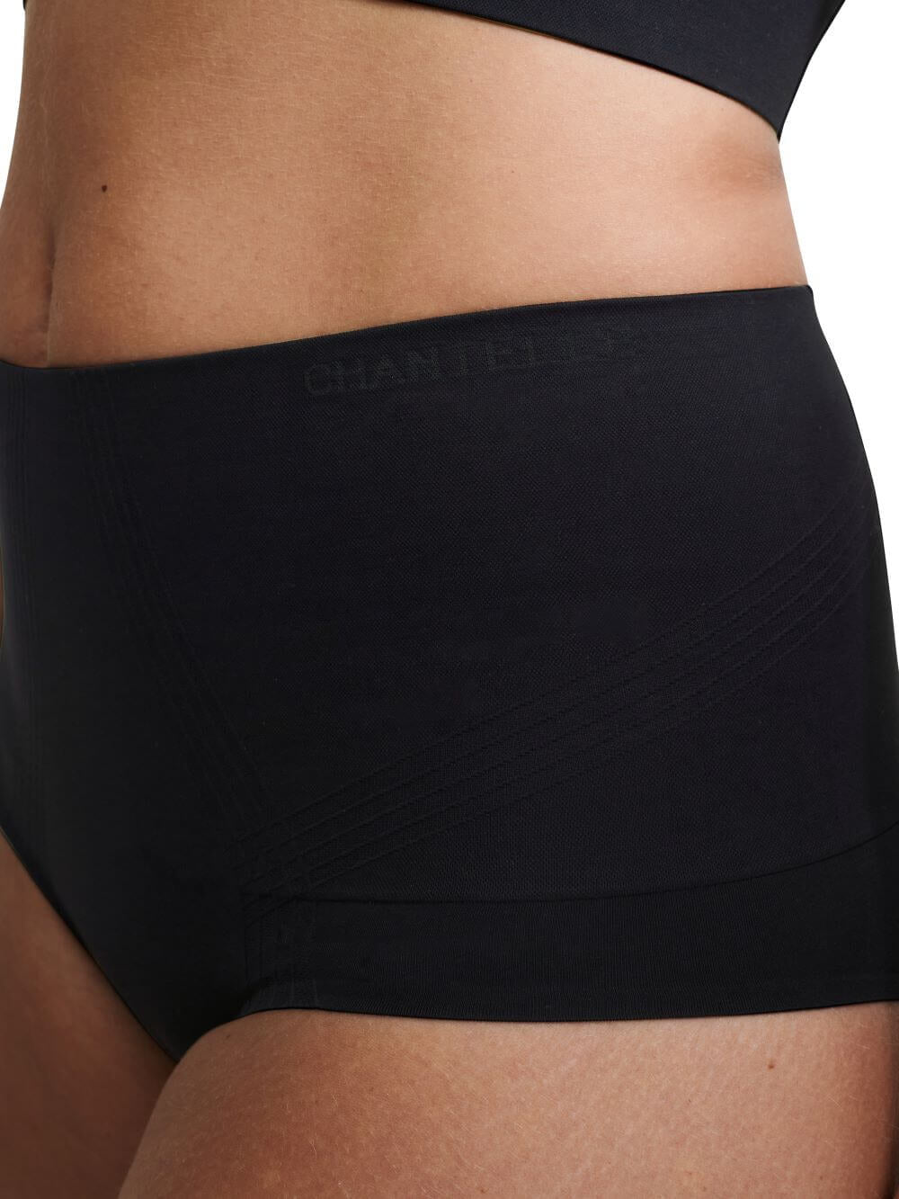 Nærbillede af en person, der bærer Chantelle Smooth Comfort Sort-figurformende undertøj, der giver et elegant, sømløst look.